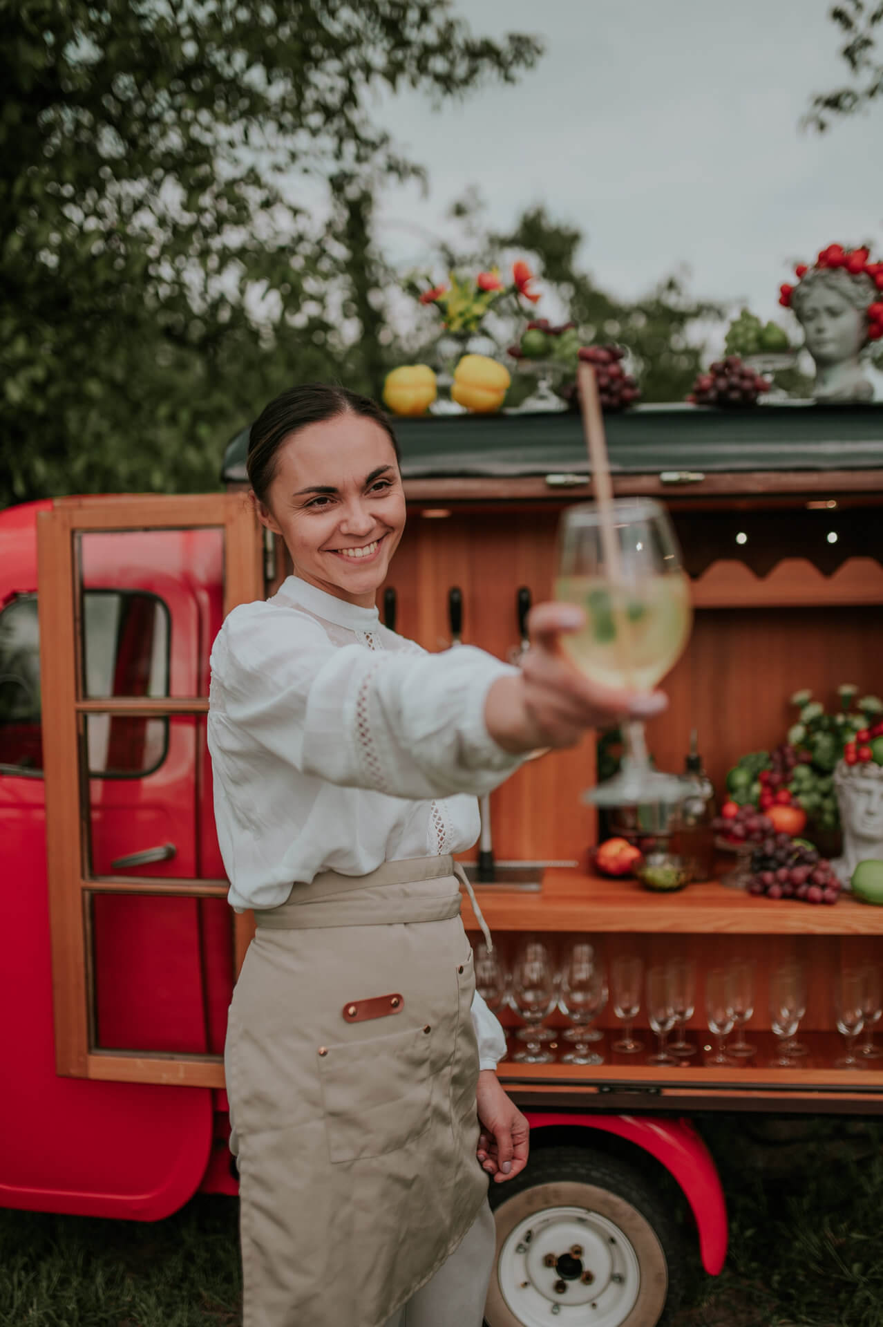 Zabytkowa czerwona Vespa Bar Frizzanti ustawiona w ogrodzie, gotowa do obsługi eventu i kontaktu z klientami.