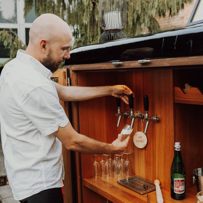 Barman nalewający schłodzone wino musujące prosto z kranu w drewnianym wnętrzu mobilnego baru Frizzanti.