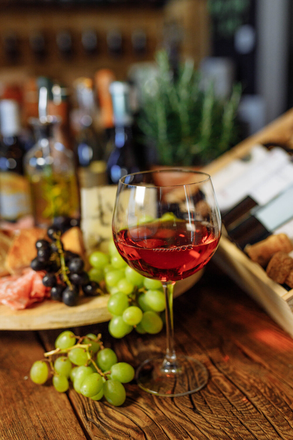 Kieliszek wysokiej jakości czerwonego wina na rustykalnym stole na tle włoskich przekąsek antipasti i drewnianej skrzynki. Dobór win do menu restauracji i hoteli od Frizzanti.